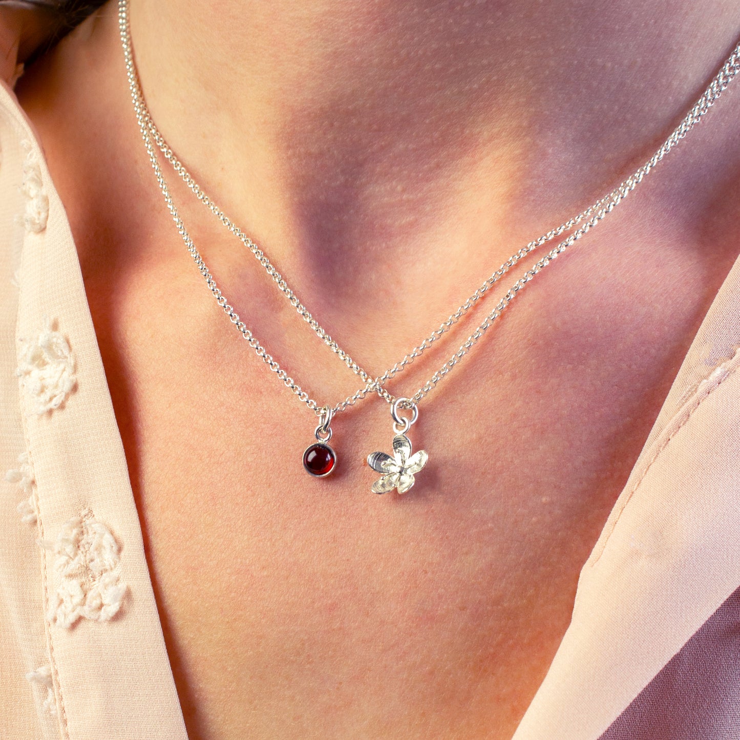 Zilveren ketting met granaat in combinatie met zilveren ketting met bloem bedel.