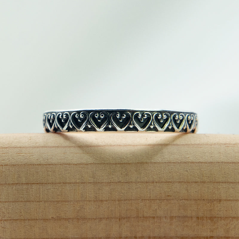 Zilveren ring met sierlijk hartjes patroon.