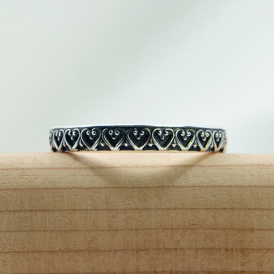 Zilveren ring met sierlijk hartjes patroon.