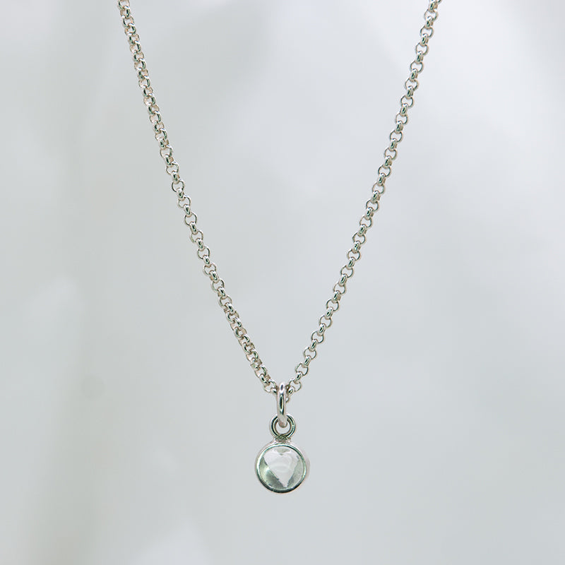 Zilveren ketting met 5 mm cabochon geslepen witte kwarts in zilveren hanger met hart detail aan de achterkant.