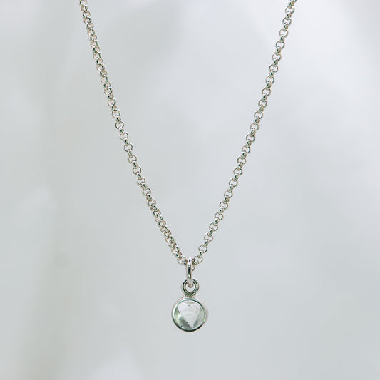 Zilveren ketting met 5 mm cabochon geslepen witte kwarts in zilveren hanger met hart detail aan de achterkant.