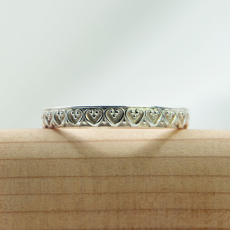 Zilveren ring met sierlijk hartjes patroon.